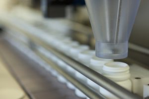 Funnel Over Bottles on Production Line at Pharmaceutical Factory